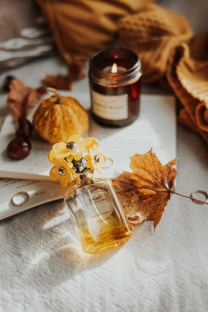 brown-dried-leaf-beside-glass-perfume-bottle-6729087 Warm autumn still life featuring perfume, candle, leaf, and pumpkin on rustic linen.