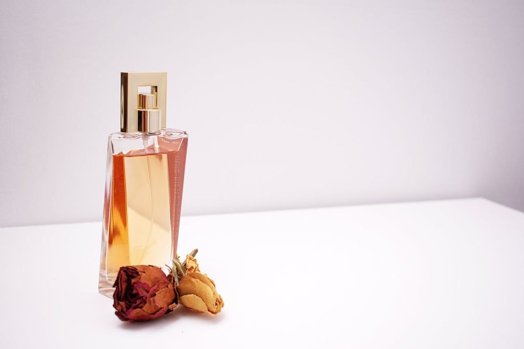 clear-glass-perfume-bottle-1190829 Elegant glass perfume bottle with luxurious design placed next to dried flowers against a minimalistic white background.