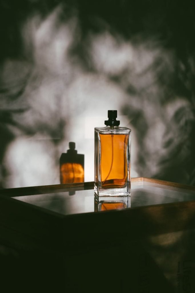 photo-of-perfume-3059609 A stylish perfume bottle casting shadows on a reflective surface, creating a moody ambiance.